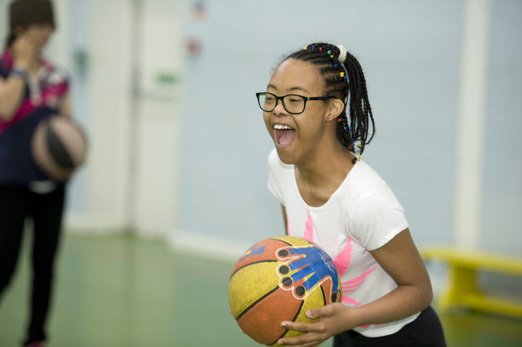Young girl playing basketball in sports hall